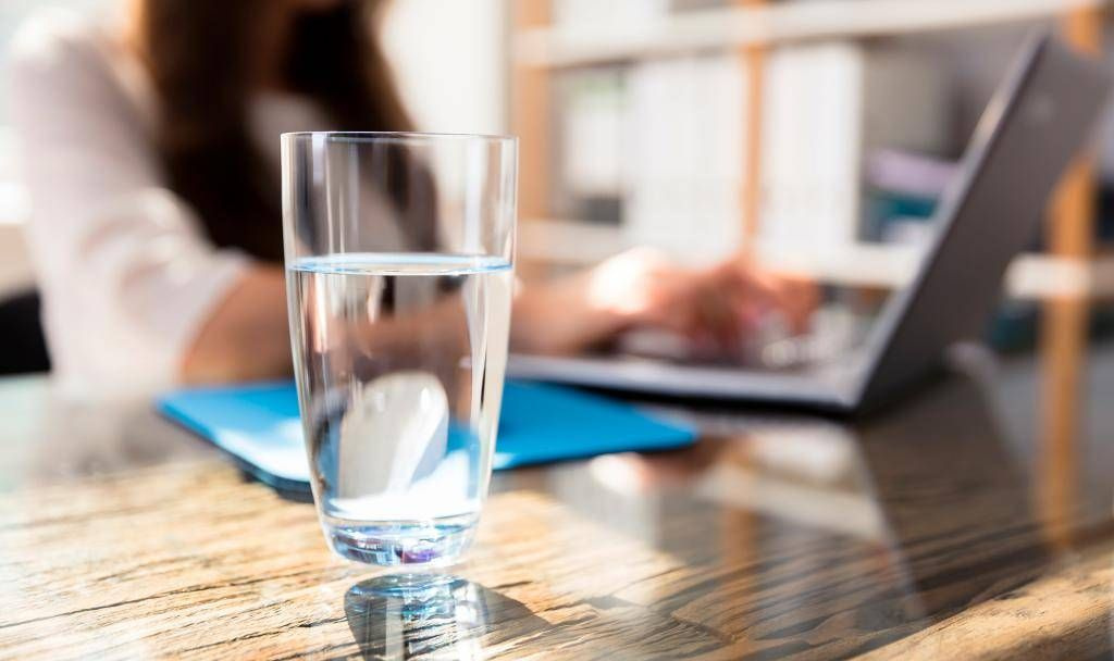 Glass of water on a bright table with notebook